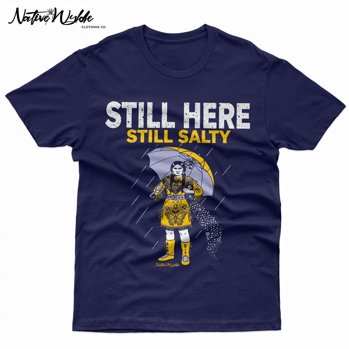 A navy blue short-sleeve T-shirt with a graphic print of a woman in a yellow dress holding an umbrella in the rain, with the text 'STILL HERE STILL SALTY' in white and yellow. 