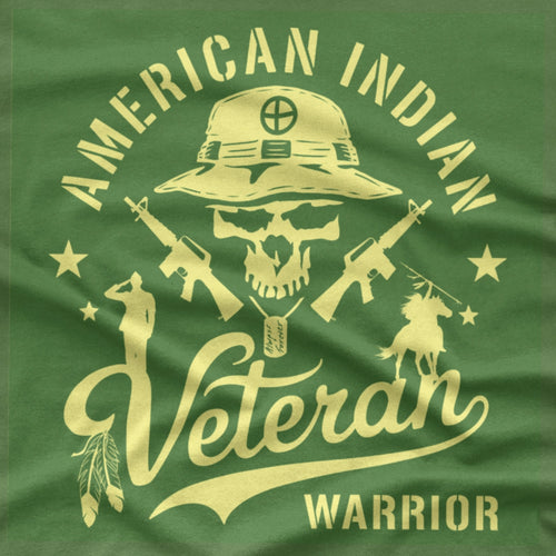 An army green short-sleeve T-shirt with a large graphic print on the front. The graphic features a skull wearing a military boonie hat, crossed rifles, and the words 'AMERICAN INDIAN Veteran WARRIOR' in a bone color.