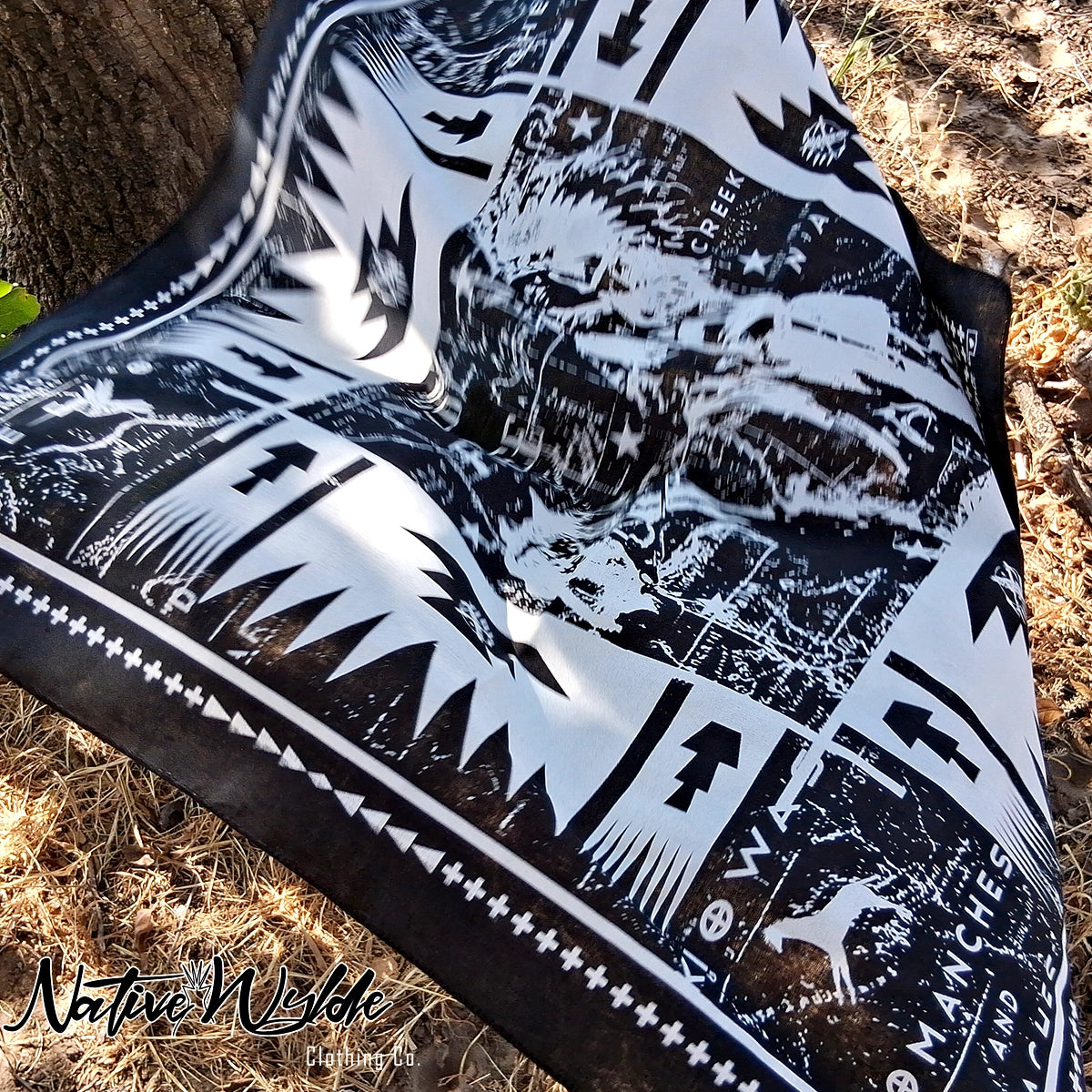 A square black and white bandana with a Southwestern geometric pattern, featuring a central graphic of a Native American warrior and text including  'WILD AND FREE'.