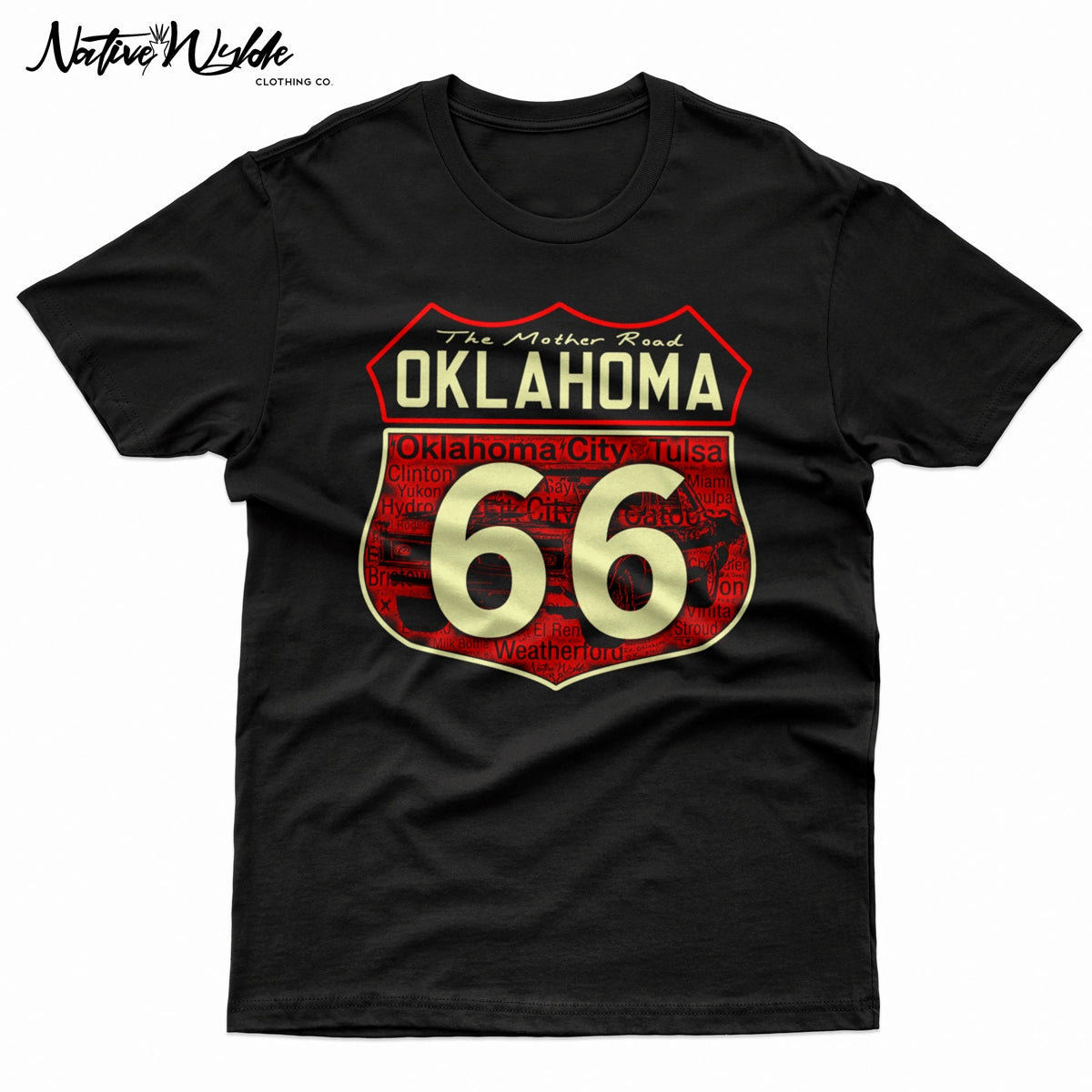 A close-up of a black shirt featuring a large graphic print of the Oklahoma Route 66 shield. The design has bonecolored text and numbers outlined in red, with 'The Mother Road OKLAHOMA' at the top and 'Oklahoma City Tulsa' in the background shield, along with other Oklahoma cities Route 66 travel through.