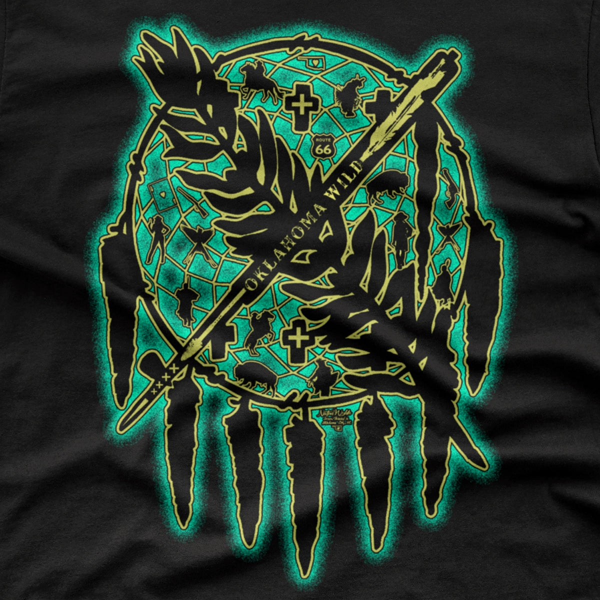 A black short-sleeve crewneck t-shirt featuring a large graphic print of a dreamcatcher with an arrow and leaf design in blue and bone colors.