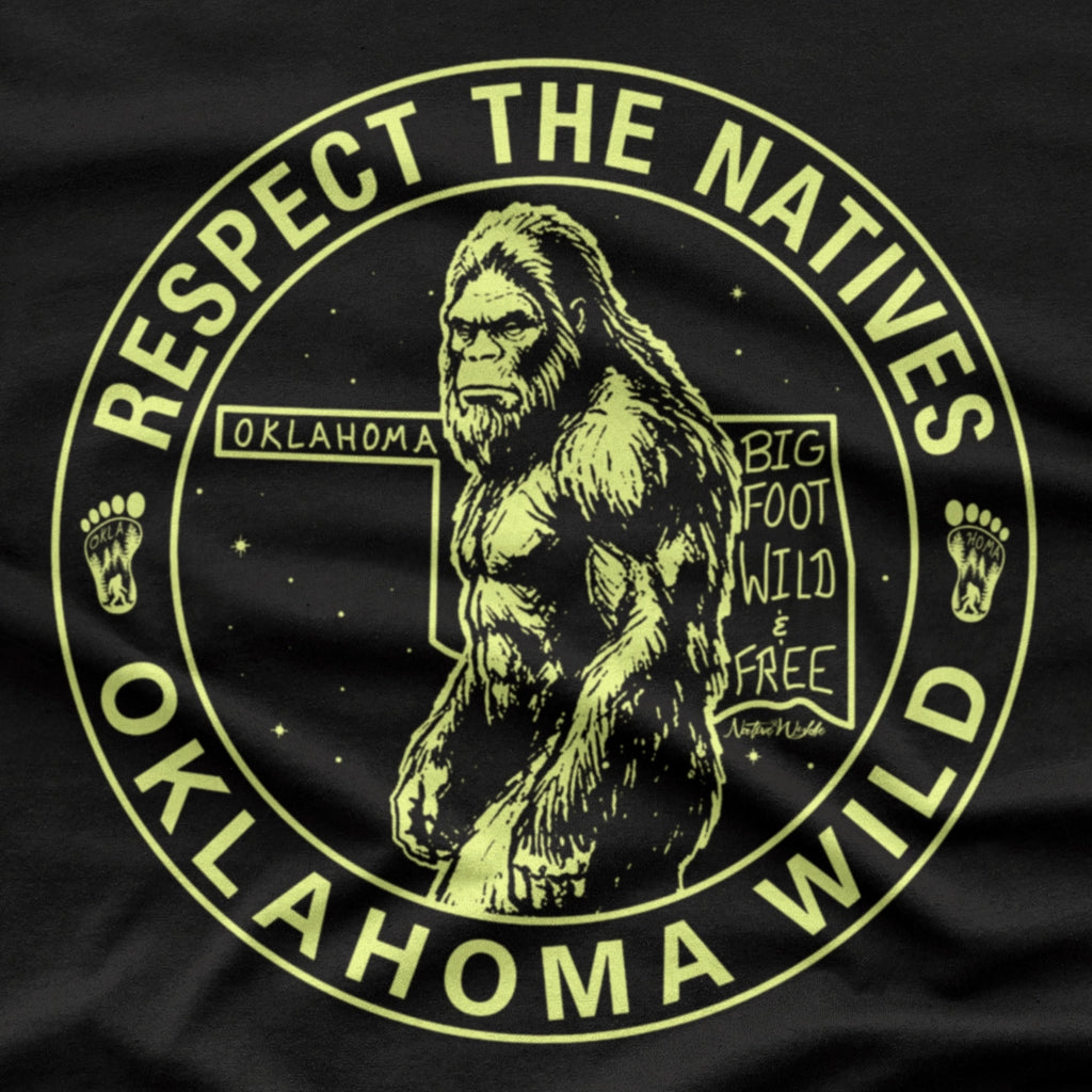 A black short-sleeve crewneck t-shirt featuring a circular graphic print of Bigfoot in the center with the text 'RESPECT THE NATIVES' and 'OKLAHOMA WILD' in bone color around the border. 