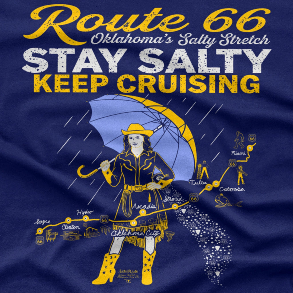 A navy blue graphic print featuring a stylized Route 66 theme with the text 'Route 66 Oklahoma's Salty Stretch', 'STAY SALTY', and 'KEEP CRUISING'. The design includes a woman holding a yellow umbrella, a map with labeled cities, and distressed yellow and white lettering.