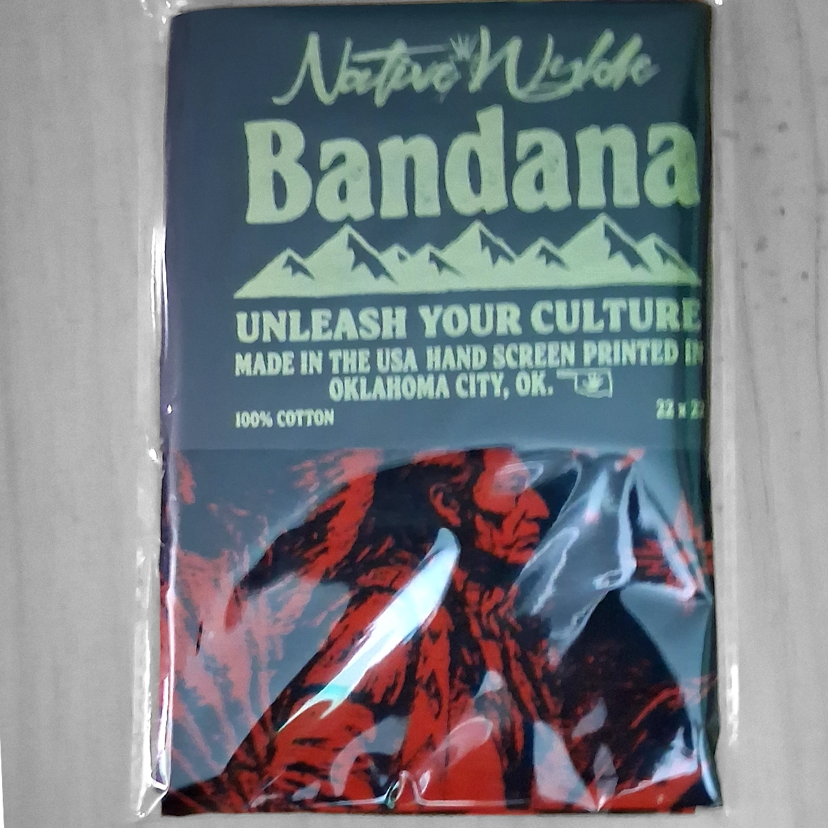 A packaged Native Waffle Bandana featuring a dark blue and red graphic print of a Native American figure, sealed in clear plastic on a light gray background.