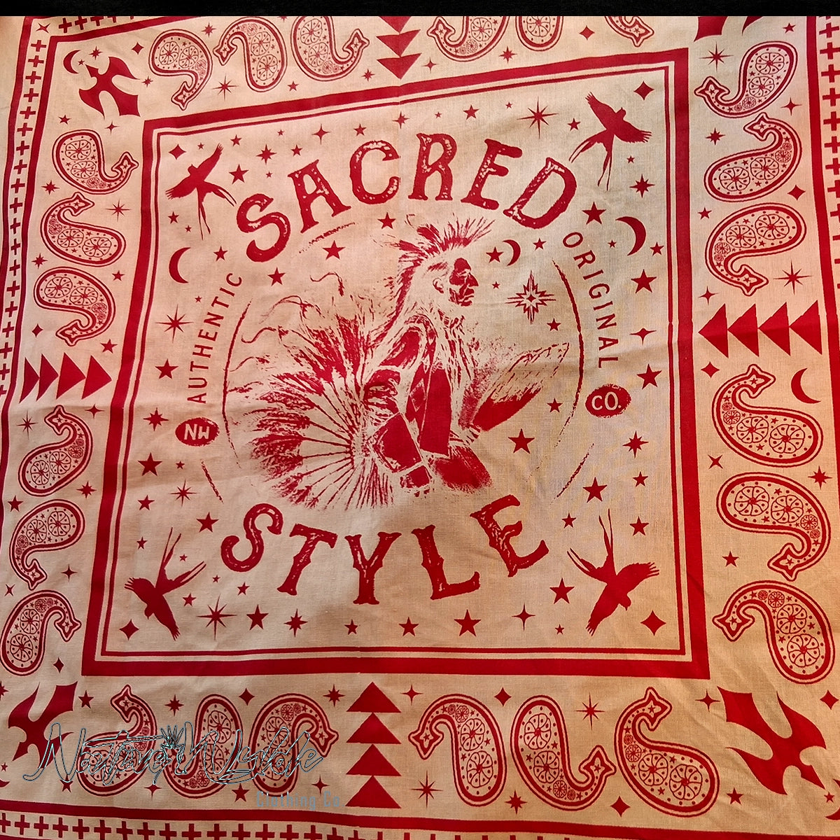 A square bandana-style textile laid flat, featuring a red western-inspired print with the words 'Sacred Style,' stars, moons, geometric motifs, and a central rooster illustration on a cream background.
