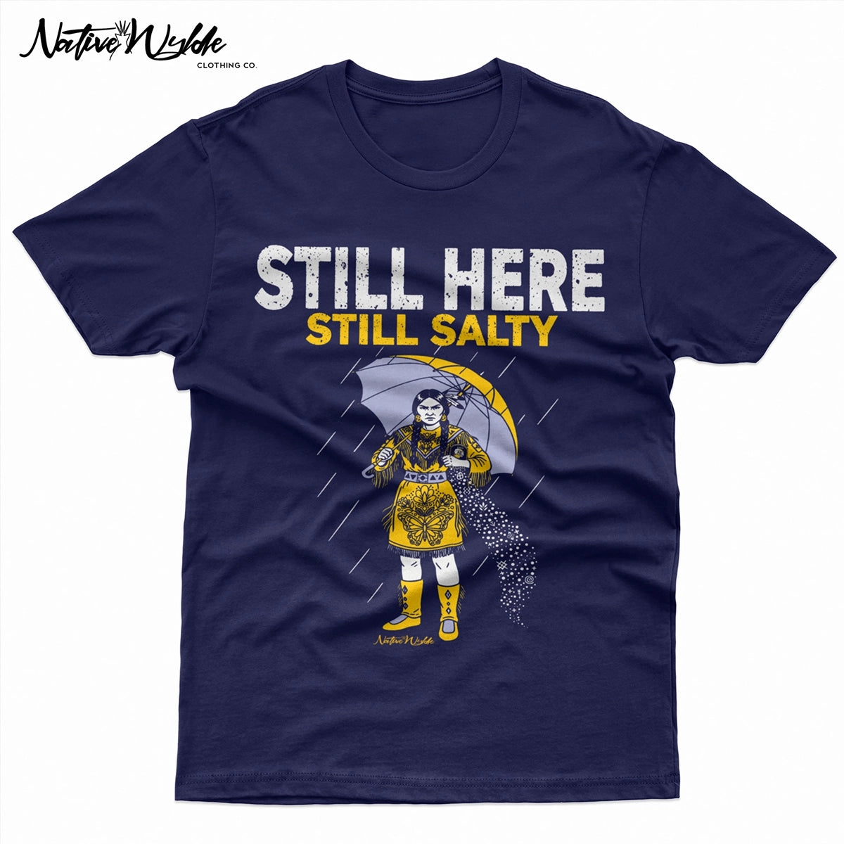 A navy blue short-sleeve T-shirt with a graphic print of a woman in a yellow dress holding an umbrella in the rain, with the text 'STILL HERE STILL SALTY' in white and yellow. 