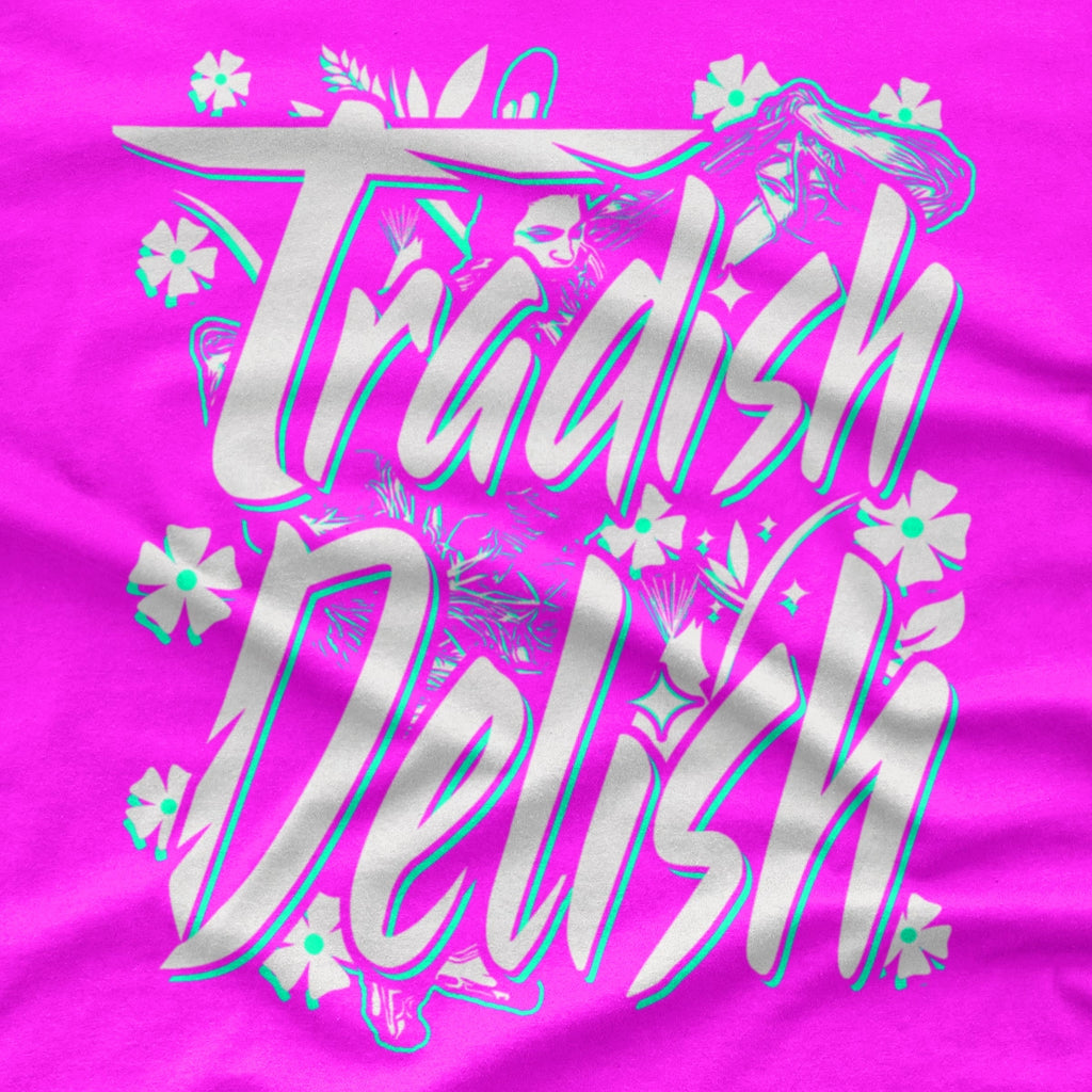 A bright pink crewneck t-shirt featuring a large graphic on the front that reads 'Tradish Delish' in stylized white and light blue lettering with small floral accents and a Native American Shawl Dancer.