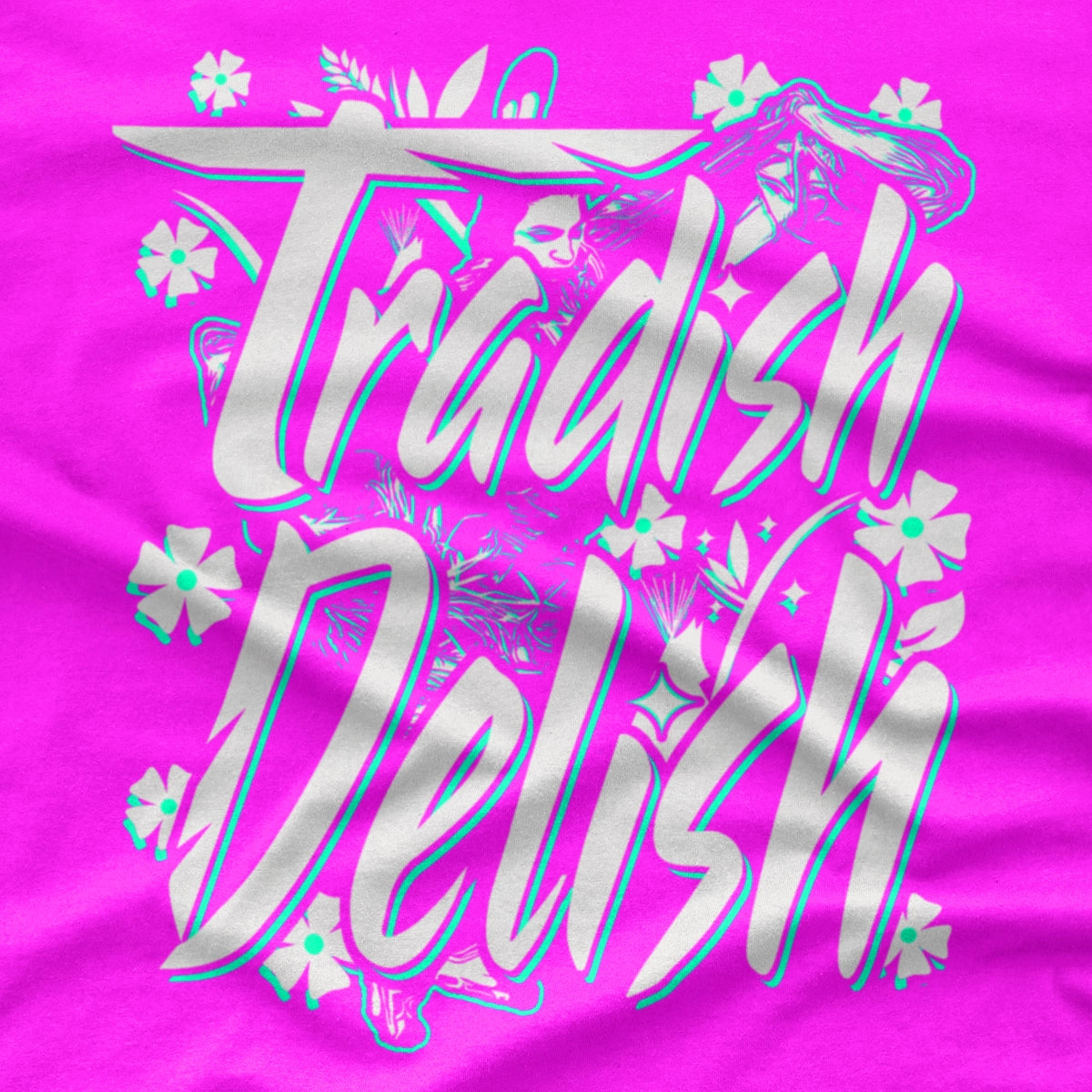 A bright pink crewneck t-shirt featuring a large graphic on the front that reads 'Tradish Delish' in stylized white and light blue lettering with small floral accents and a Native American Shawl Dancer.